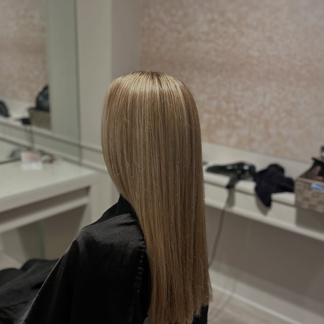 Glad, steil blond haar voor de spiegel in de salon